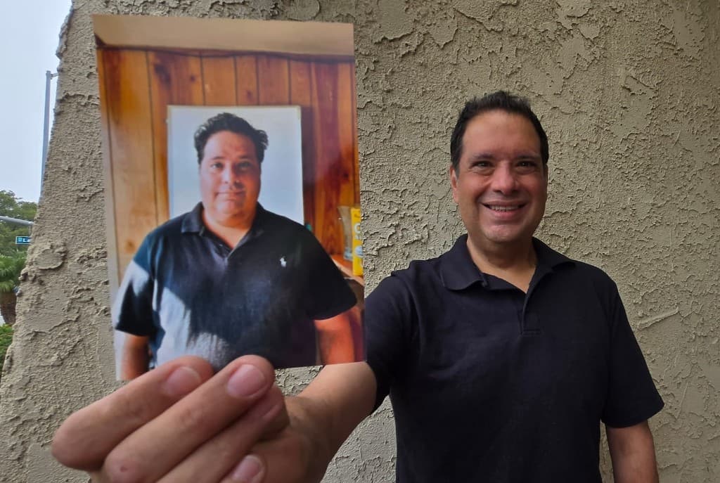 Gary Isse holding a before photo showing his 100 pound weight loss transformation
